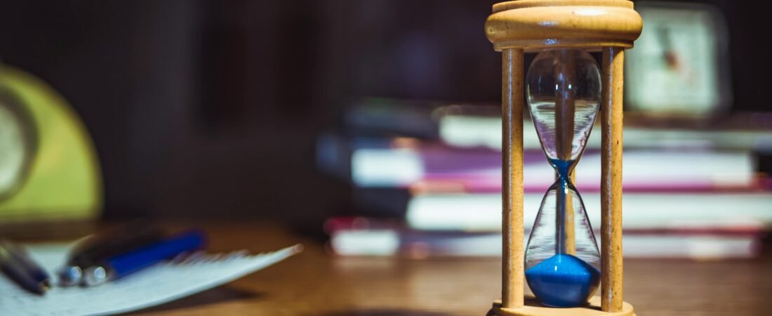Hourglass on a desk with books, representing how long it takes to learn Romanian
